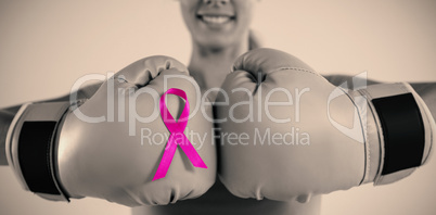 Mid section of smiling woman with boxing gloves and pink ribbon