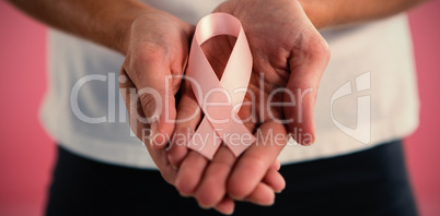 Mid section of woman holding pink ribbon