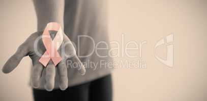 Mid section of woman holding pink breast cancer awareness ribbon