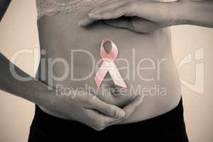 Mid section of woman with ribbon on abdomen
