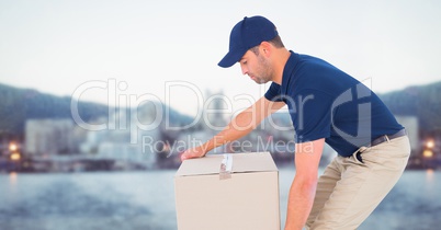 Delivery man picking up box against blurry skyline