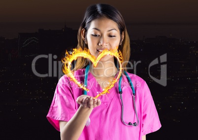 nurse with hand spread of with heart fire icon over in front of the city at night.