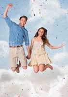 Couple jumping in air against blurry sky and confetti