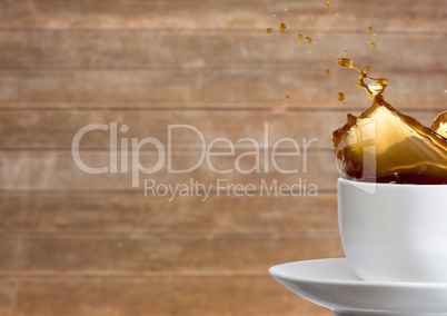 White cup with coffee splashing against blurry wood panel