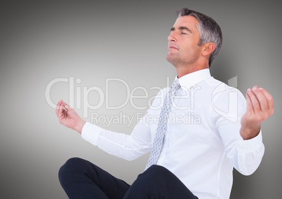 Business man meditating against grey background