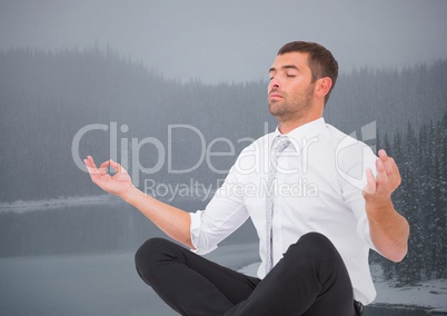 Business man meditating against misty river and trees with grey sky