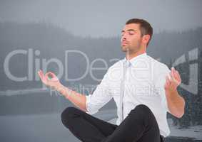 Business man meditating against misty river and trees with grey sky