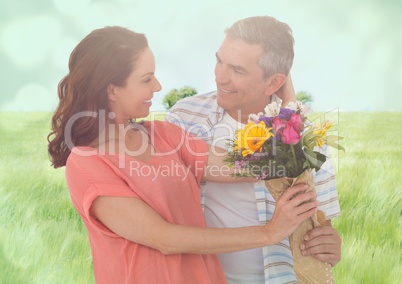 Middle aged couple with flowers in blurry meadow