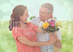 Middle aged couple with flowers in blurry meadow