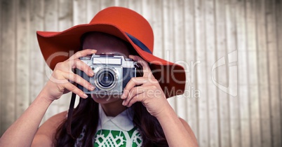 Close up of millennial woman with camera in Summer hat against blurry wood panel