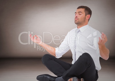 Business man meditating against pink wall
