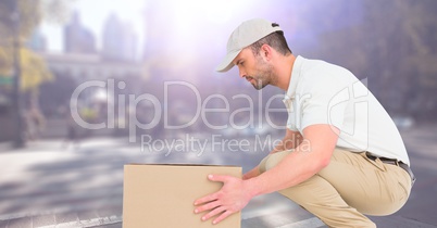 Delivery man picking up box against blurry street with flare