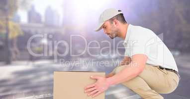 Delivery man picking up box against blurry street with flare