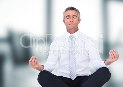 Business man meditating against blurry office