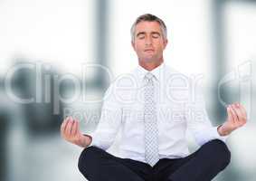 Business man meditating against blurry office