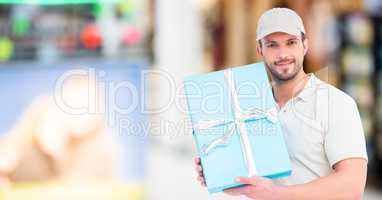 Delivery man with blue gift against blurry shopping center