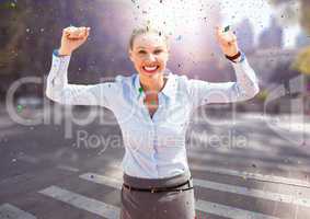 Business woman hands in air on blurry street with flares and confetti