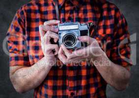 Millennial man mid section with camera against grey background with grunge overlay