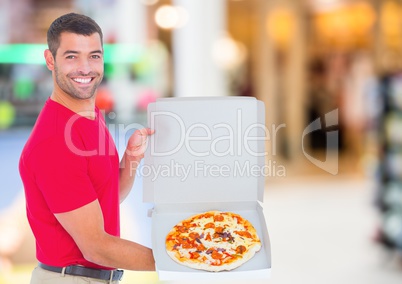 Delivery man with pizza against blurry shopping centre