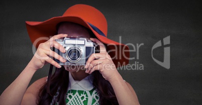 Close up of millennial woman with camera in Summer hat against grey wall
