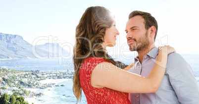 Couple embracing against blurry coastline with flare