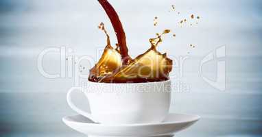 Coffee being poured into white cup against blurry blue wood panel