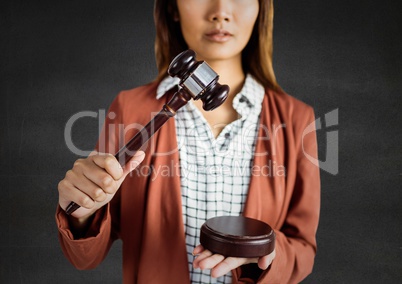 Female judge with gavel against grey wall