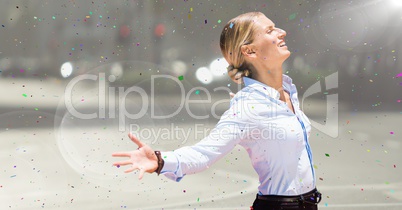 Business woman arms outstretched against blurry street with flare and confetti