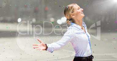 Business woman arms outstretched against blurry street with flare and confetti