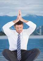 Business man meditating against water and mountains