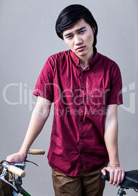 Millennial man with bike against grey background