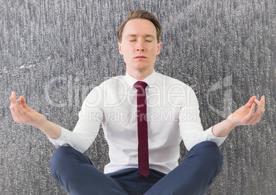 Business man meditating against grey trees