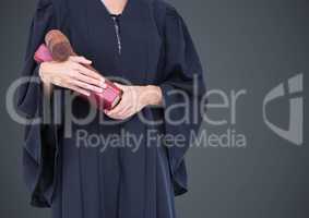 Female judge mid section with book and gavel against grey background