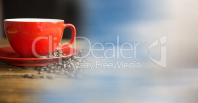 Red coffee cup with beans and blurry sky transition