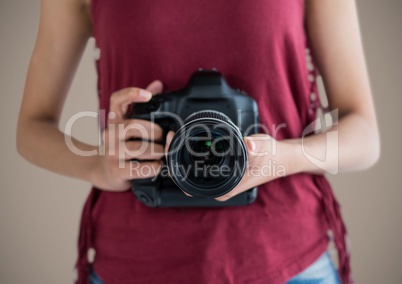 Millennial woman mid section with camera against brown background