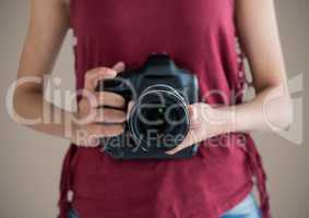 Millennial woman mid section with camera against brown background