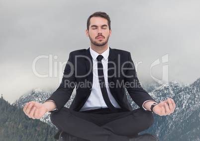 Business man meditating  against snowy mountains