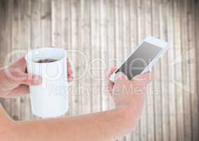 Hands with coffee and phone against blurry wood panel