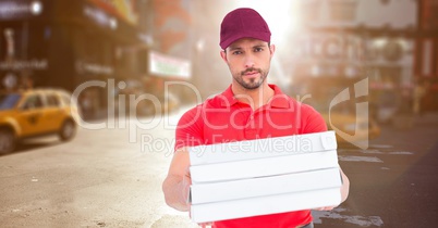 Delivery man with pizza boxes against blurry street with flare