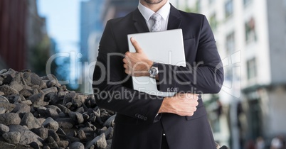 Rubble stones in city with businessman holding laptop