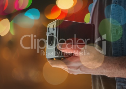 photographer hands with vintage camera at night. Color blurred lights behind and overlap.