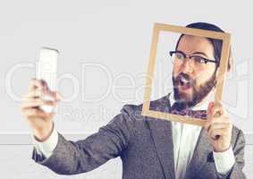Millennial man holding picture frame and phone