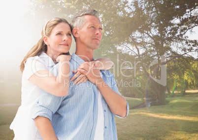 Middle aged couple embracing in blurry park with flare