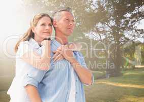 Middle aged couple embracing in blurry park with flare