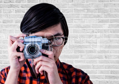 Close up of millennial man with camera against white brick wall