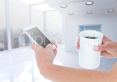 Hands with coffee and phone against blurry white office