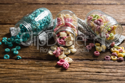 Scattered honeycomb cereals from jar on wooden table