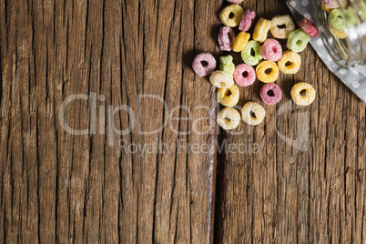 Scattered cereal rings from jar on wooden table