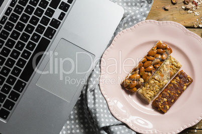 Dry fruit bars and laptop on wooden table