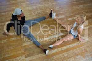 Full length of dancers stretching legs in studio